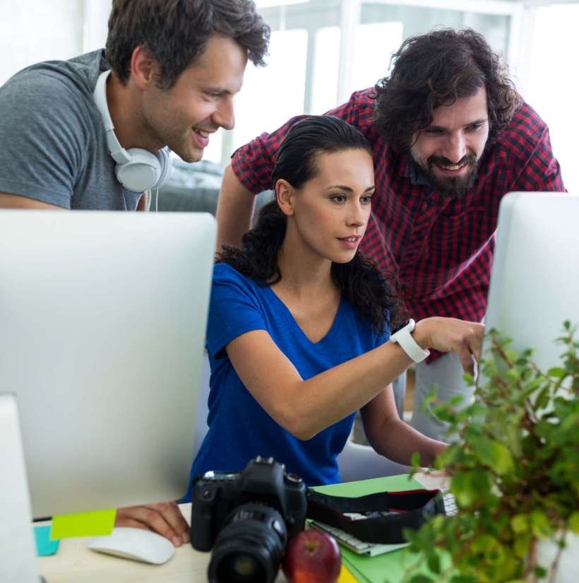 Group of graphic designers interacting over computer in office
